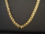 un gros plan d'un collier à chaîne dorée posé sur une surface noire