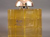 yellow perfume bottle with a silver lid on a gray surface