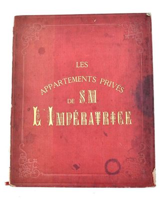an old red book with gold writing on it sitting on a white surface