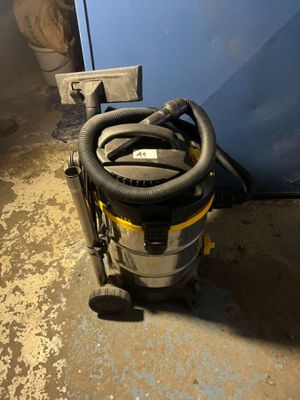 L'aspirateur est posé par terre à côté de la porte bleue.