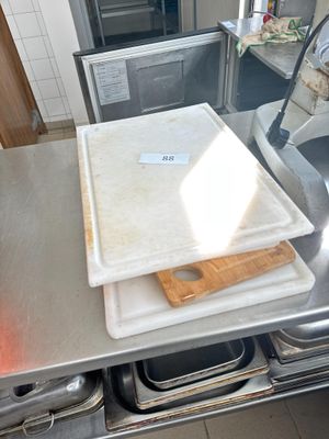 un plan de travail en acier inoxydable sur lequel est posée une planche à découper, dans une cuisine