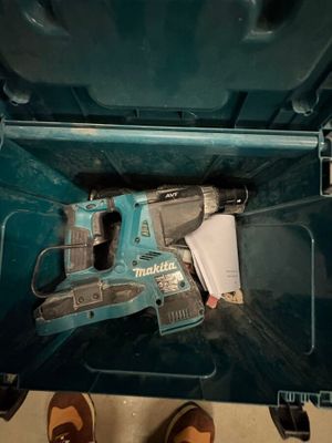une boîte à outils bleue contenant une perceuse sans fil et une paire de chaussures marron
