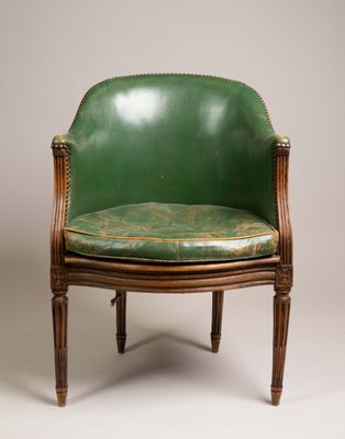 un fauteuil en cuir vert avec une structure et des pieds en bois
