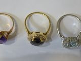 three rings with different colored stones sitting on top of a table