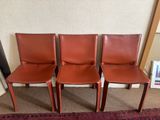 three brown leather chairs sitting next to each other on a rug