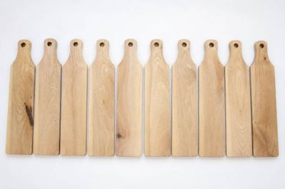 six pagaies en bois alignées sur un fond blanc
