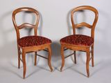 deux chaises en bois aux assises rembourrées rouges, adossées à un mur blanc