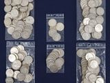 four bags filled with silver coins sitting on top of a blue surface