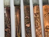 five knives with different designs are lined up on a white surface