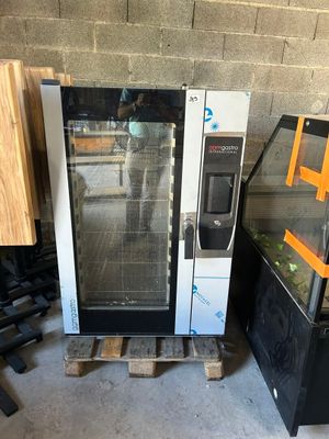 un four noir et blanc posé sur une palette à côté d'autres appareils électroménagers