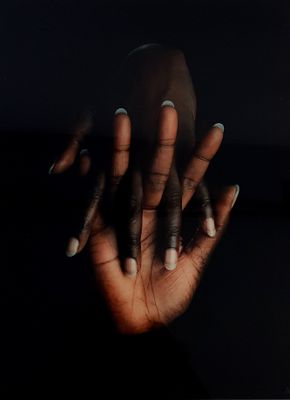 woman ' s hands with black nails and white manicures against a black background