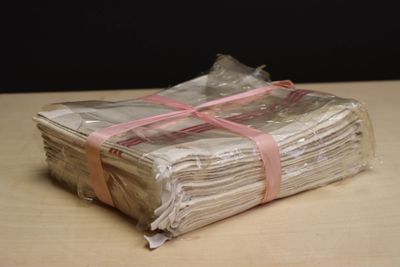a stack of papers wrapped in plastic with a pink ribbon