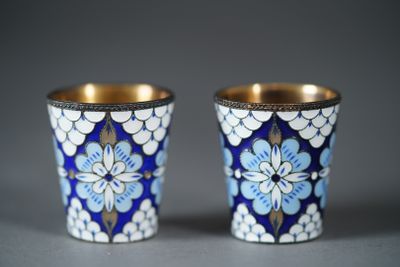 two blue and white cups with gold rims on a gray surface