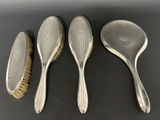 three silverplated brushes and a brush on a black surface
