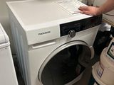 un homme debout à côté d'un lave-linge et d'un sèche-linge