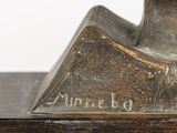a bronze statue of a bird on a wooden table