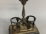 an antique silver plate with a candle holder and two cups on it