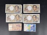 six different bills of different colors and designs on a black surface