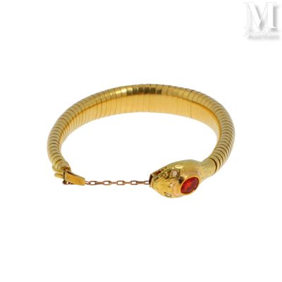 une photo d'un bracelet en forme de serpent en or, orné d'une pierre rouge au centre