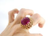 a woman ' s hand holding a ring with a ruby stone on it