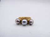 a close up of a ring with three pearls on it