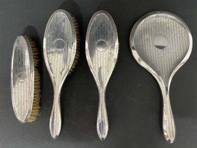 trois cuillères en argent et une brosse posées sur une table
