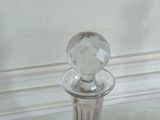 a glass decanter sitting on a table next to a glass vase