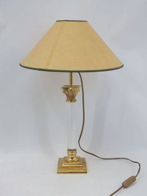 une photo d'une lampe de table avec un pied en verre et un abat-jour doré