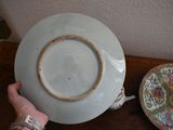 a person holding a plate on a table next to a bowl