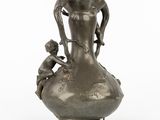 a silver vase with a statue of a woman and a child on it