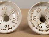 two white bowls with holes in them sitting on a table