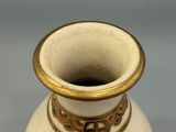 a white vase with a gold rim and a design on it
