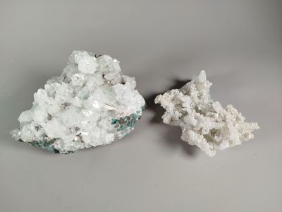 two pieces of white crystals sitting next to each other on a table