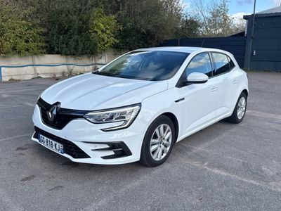 une voiture blanche garée sur un parking près d'une clôture