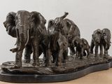 statue of a herd of elephants standing on a wooden surface