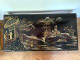 a black and gold painted box sitting on a wooden floor
