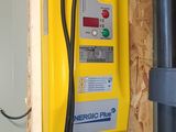 a yellow meter on the wall next to a black pipe