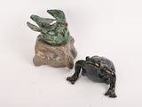 statue d'une grenouille assise sur un rocher, à côté d'une autre statue de grenouille