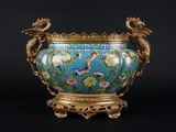 une image représentant un vase bleu muni d'une anse en forme de dragon, posé sur un socle