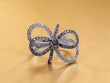 a close up of a silver bow ring on a gold surface