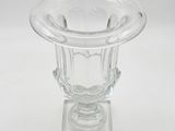 a clear glass vase on a small stand on a white surface