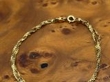 a close up of a gold bracelet on a wooden table