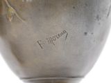 a silver vase with a bird on it on a stand