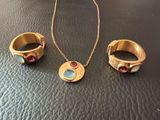 two rings and a necklace on a black leather surface