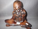 figurine en bois sculpté représentant un moine tenant un bébé sur un rocher