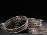 trois plats en argent posés sur une surface noire, avec un fond noir