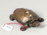 a small bronze turtle with a tag on it ' s neck