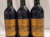 trois bouteilles de vin posées sur une nappe blanche