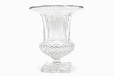un vase en verre transparent posé sur un socle, sur fond blanc