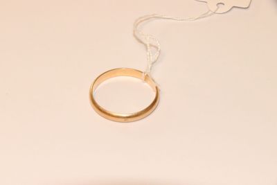 une bague en or suspendue à un fil sur une table blanche
